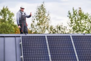 Comment choisir son kit solaire pour être autonome ? Portrait d'un technicien installant des modules solaires photovoltaïques sur le toit d'une maison.