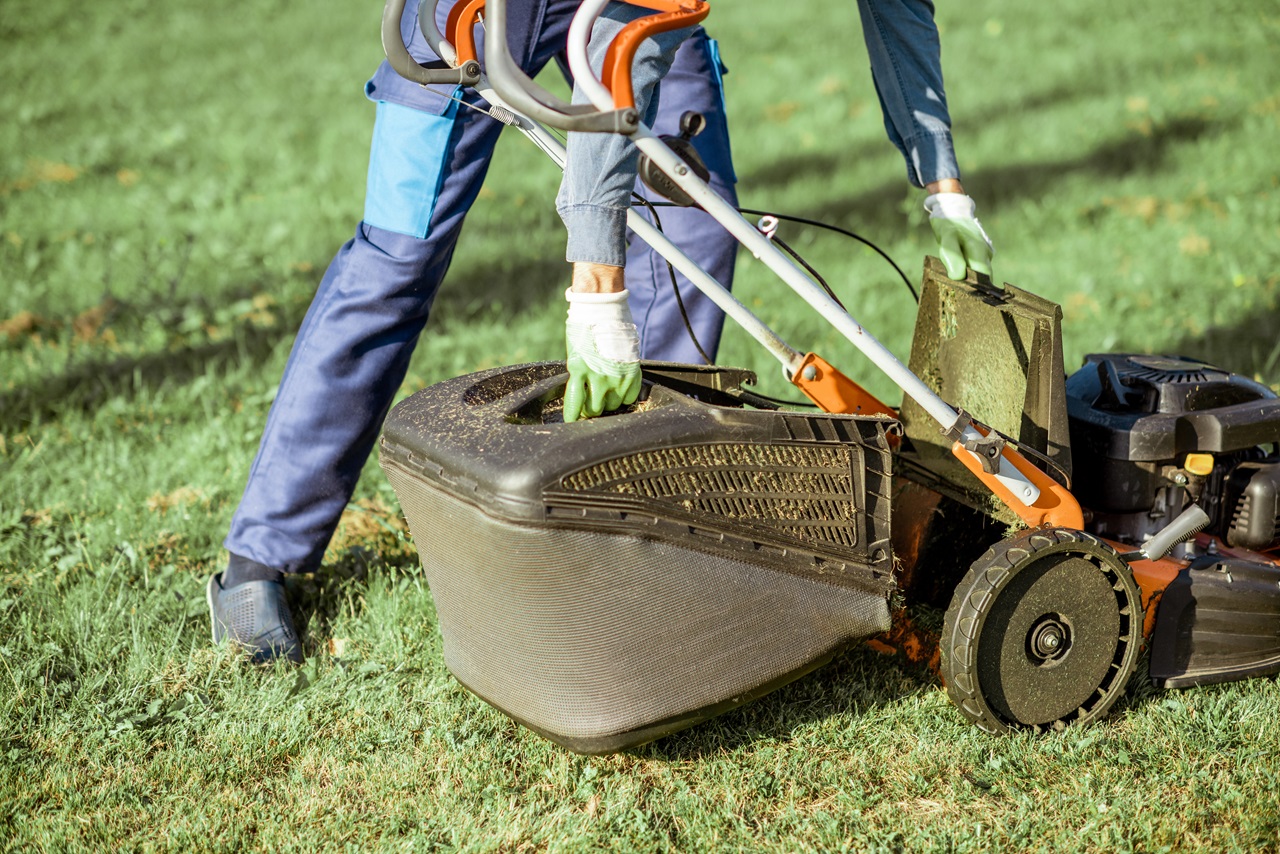 Jardinier travaillant avec une tondeuse à gazon dans le jardin